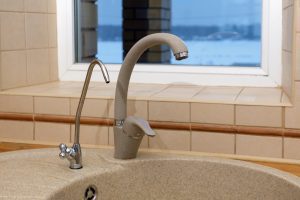 Kitchen faucet. Artificial stone sink with two taps, plain and filtered water. Fragment of modern kitchen. Filter system or osmosis, water purification in Lithia