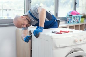 Professional repairman fixing a broken washing machine, home repair concept in Plant City, FL